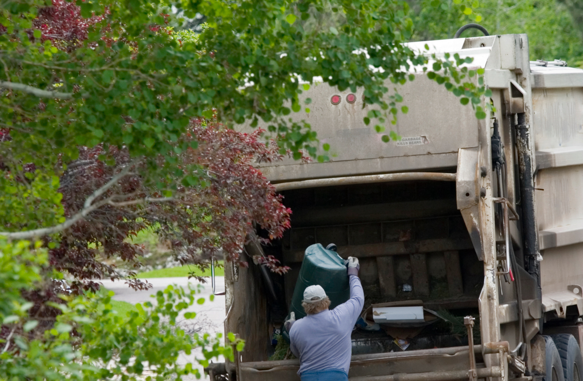 Image of Armstrong Sanitation worker dumping 96 gallon plastic cart into residential truck.